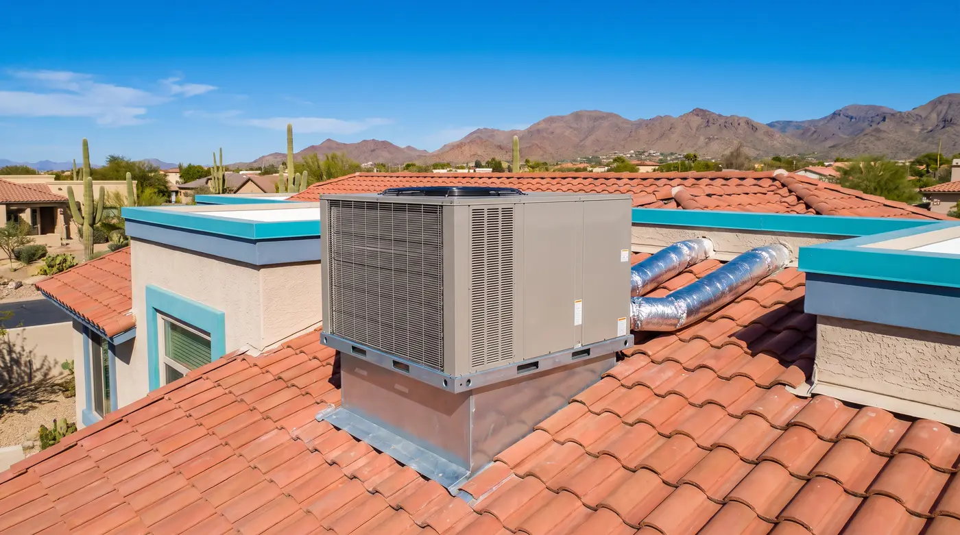 Weathered rooftop package air conditioner on a flat-roofed 1960s block home in central Phoenix